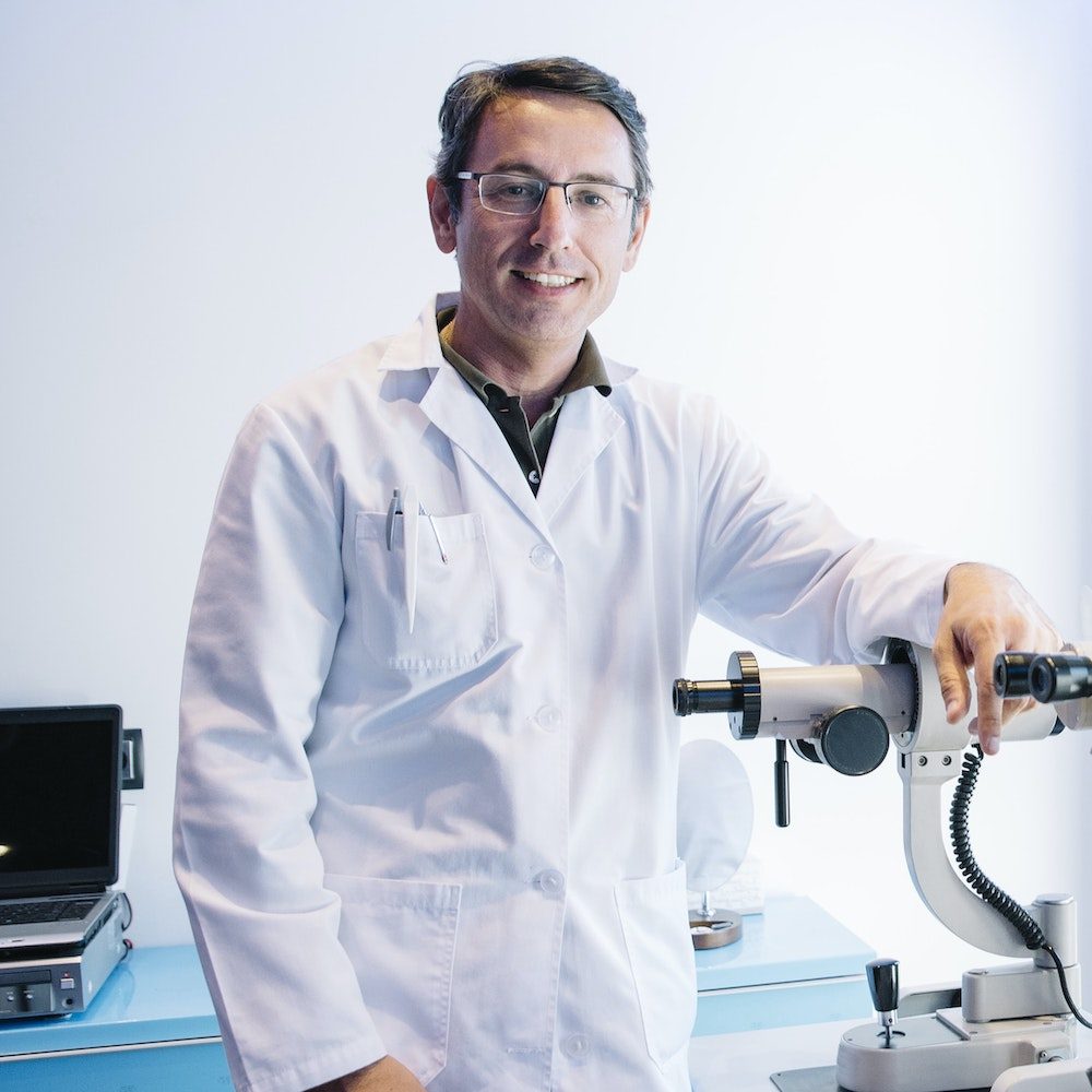 portrait-of-handsome-eye-doctor-sitting-with-ophthalmologic-device-in-the-cabinet-e1682618573640