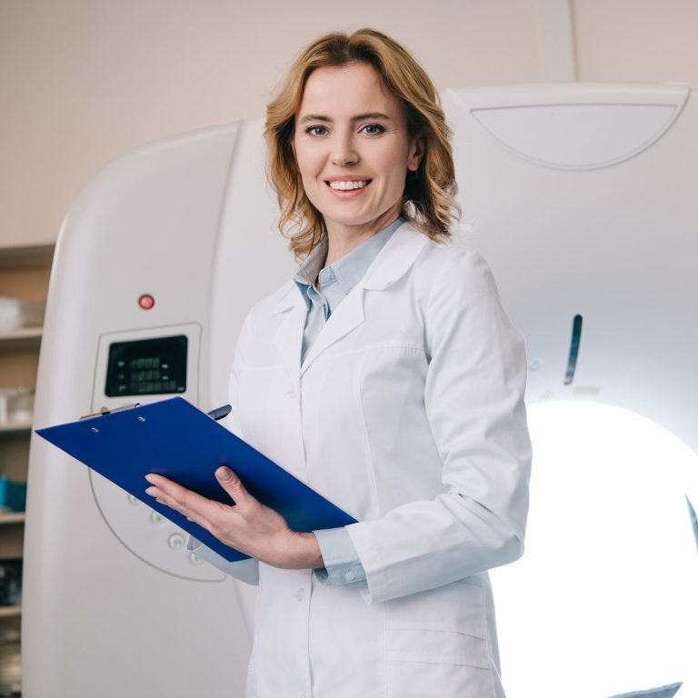 smiling-radiologists-writing-on-clipboard-while-standing-near-computed-tomography-scanner-e1682439568937