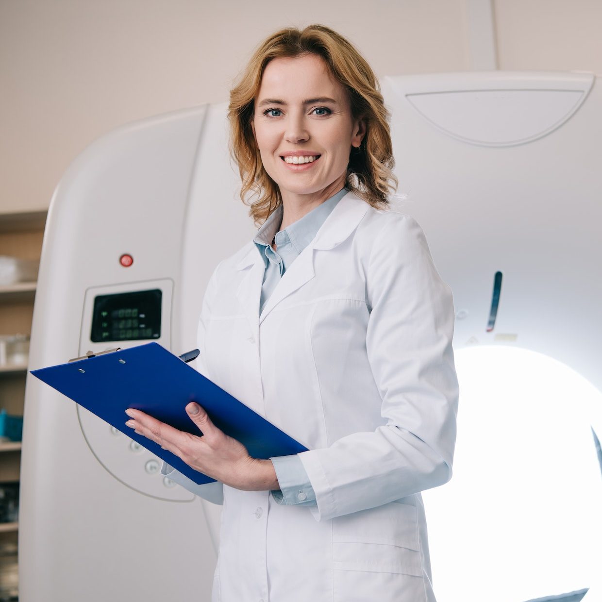 smiling-radiologists-writing-on-clipboard-while-standing-near-computed-tomography-scanner-e1682439568937